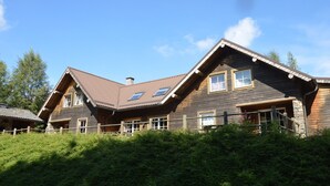 A wooden house with a sloped roof, multiple windows, and a wooden fence. - Chalet in Ovifat Near Ski Slopes (Waimes)