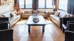 A modern living room with a sofa set, a coffee table, and a view of the outdoors through large windows. - Beautiful Holidayhome With Sauna and Terrace (Harscheid)