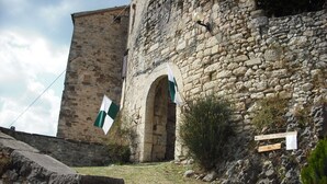 Un bâtiment en pierre doté d’une tour, d’un drapeau et d’un panneau indiquant les directions.