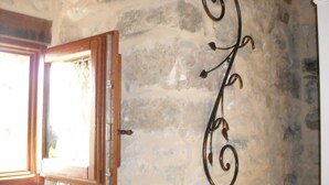Un mur en pierre agrémenté d’un élément décoratif en métal et une fenêtre avec un cadre en bois.