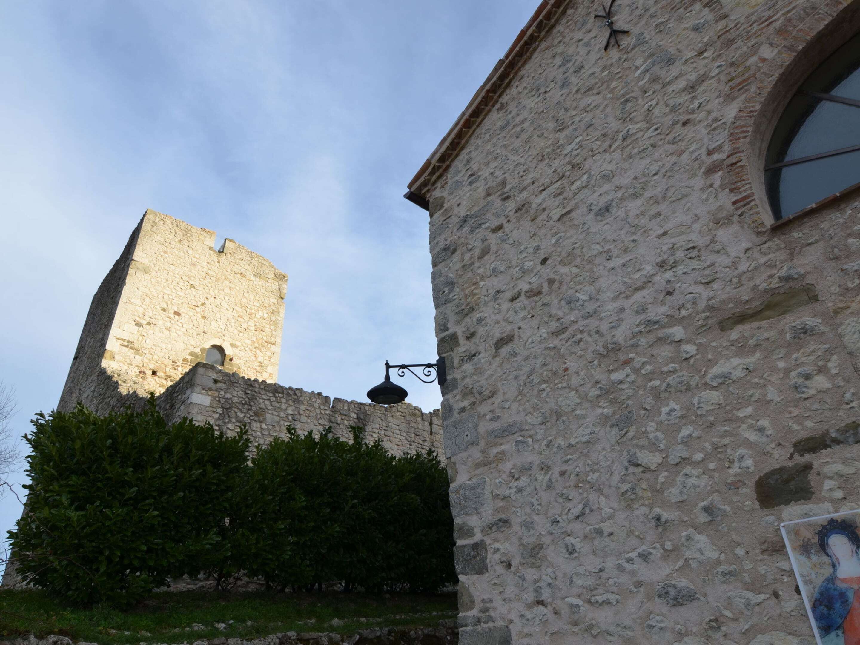 A stone building with a tall tower and a smaller building in the foreground.