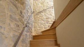 Un escalier en bois, avec des murs en pierre et une rampe métallique.