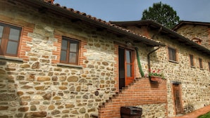 A stone building with a wooden staircase, a window with a shutter, and a brick mailbox. - Rustic Serenity Farmhouse (Monte Santa Maria Tiberina)