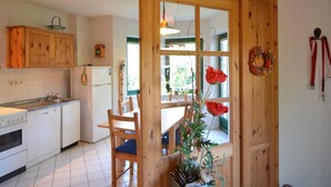 Una cocina con armarios de madera, una mesa de comedor con sillas y una ventana con vista a zonas verdes.