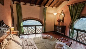 A bedroom with a large bed, a nightstand, a dresser, a mirror, and a view through a window. - Holiday Home in Dicomano (Dicomano)