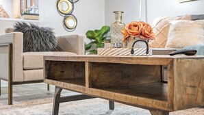 Une table basse en bois, ornée d’un vase de fleurs et d’un plateau décoratif.