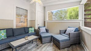 Une terrasse couverte avec un ensemble de canapés, une table basse et des chaises en osier.