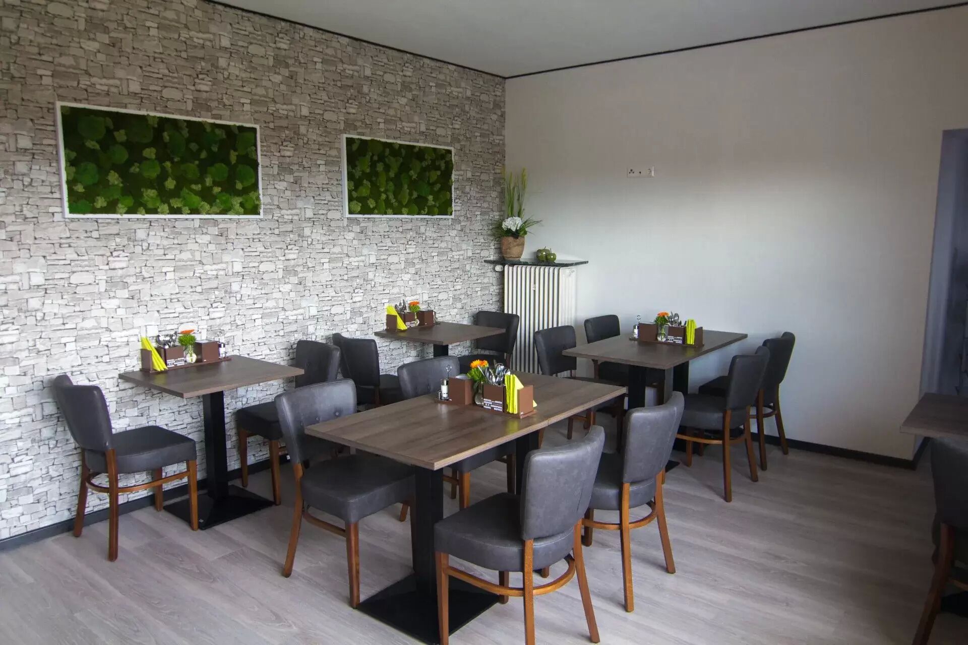 A modern dining area with a stone wall, multiple tables, and chairs.