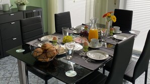 Una mesa de desayuno servida con platos, vasos, un frutero y una jarra de jugo de naranja.