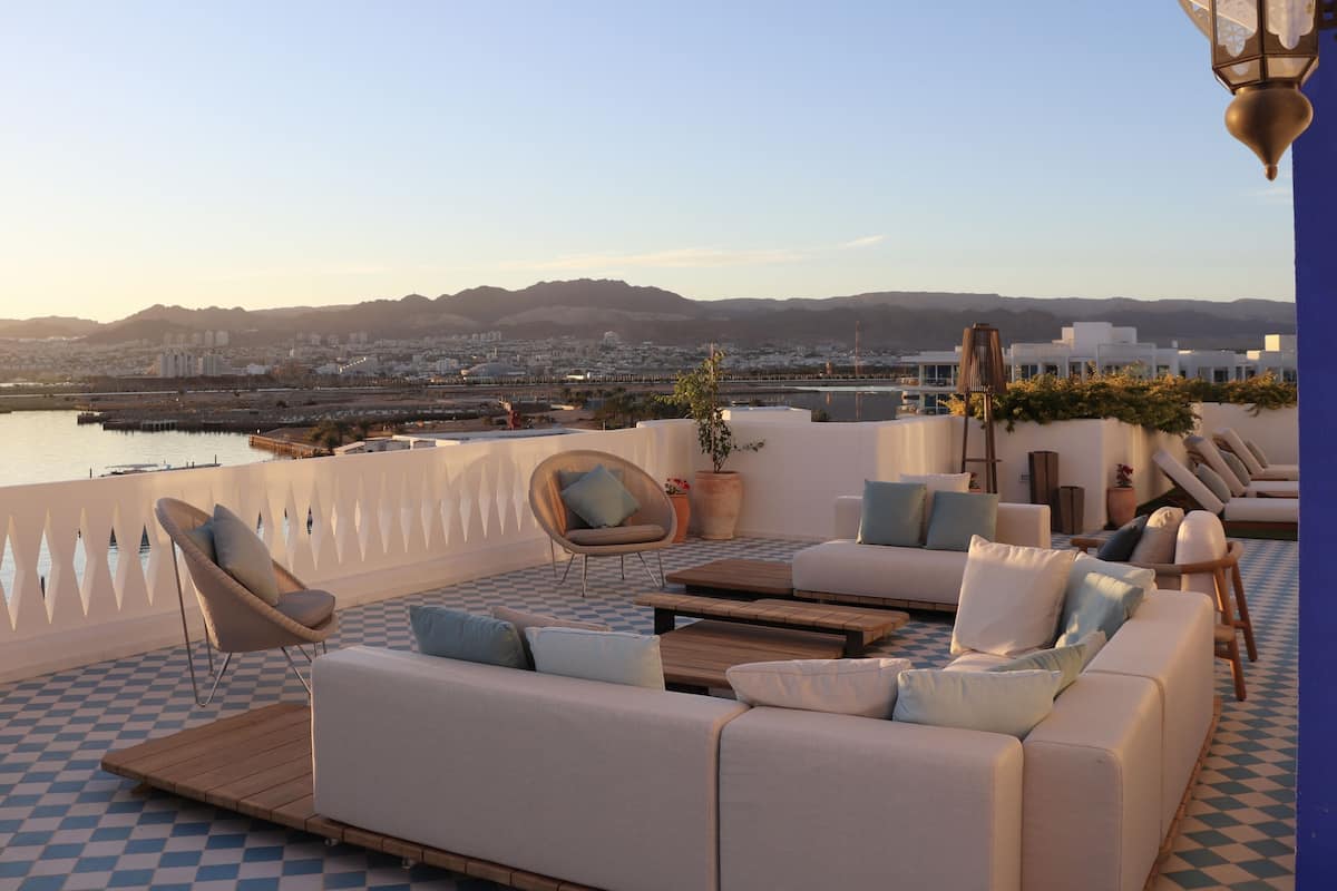 A rooftop terrace with a checkered floor, a sofa set, and lounge chairs.