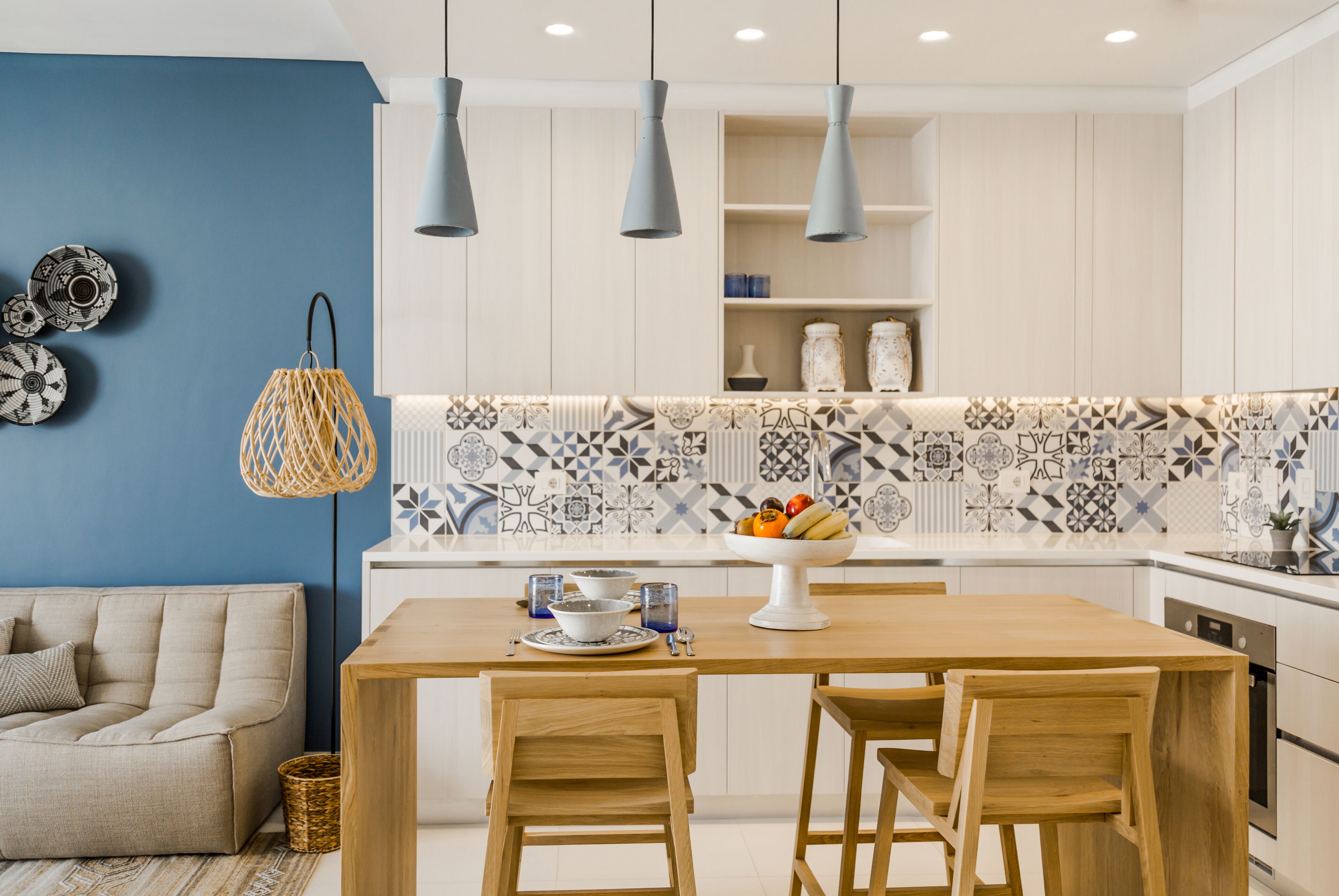 A modern kitchen with a wooden table, two chairs, and a blue wall.