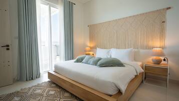 A modern bedroom with a large bed, a macrame wall hanging, and a view of the outdoors.