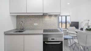 A modern kitchen with white cabinets, a granite countertop, and a backsplash with patterned tiles. - In the Funchal city center, Santa Luzia I (Funchal)