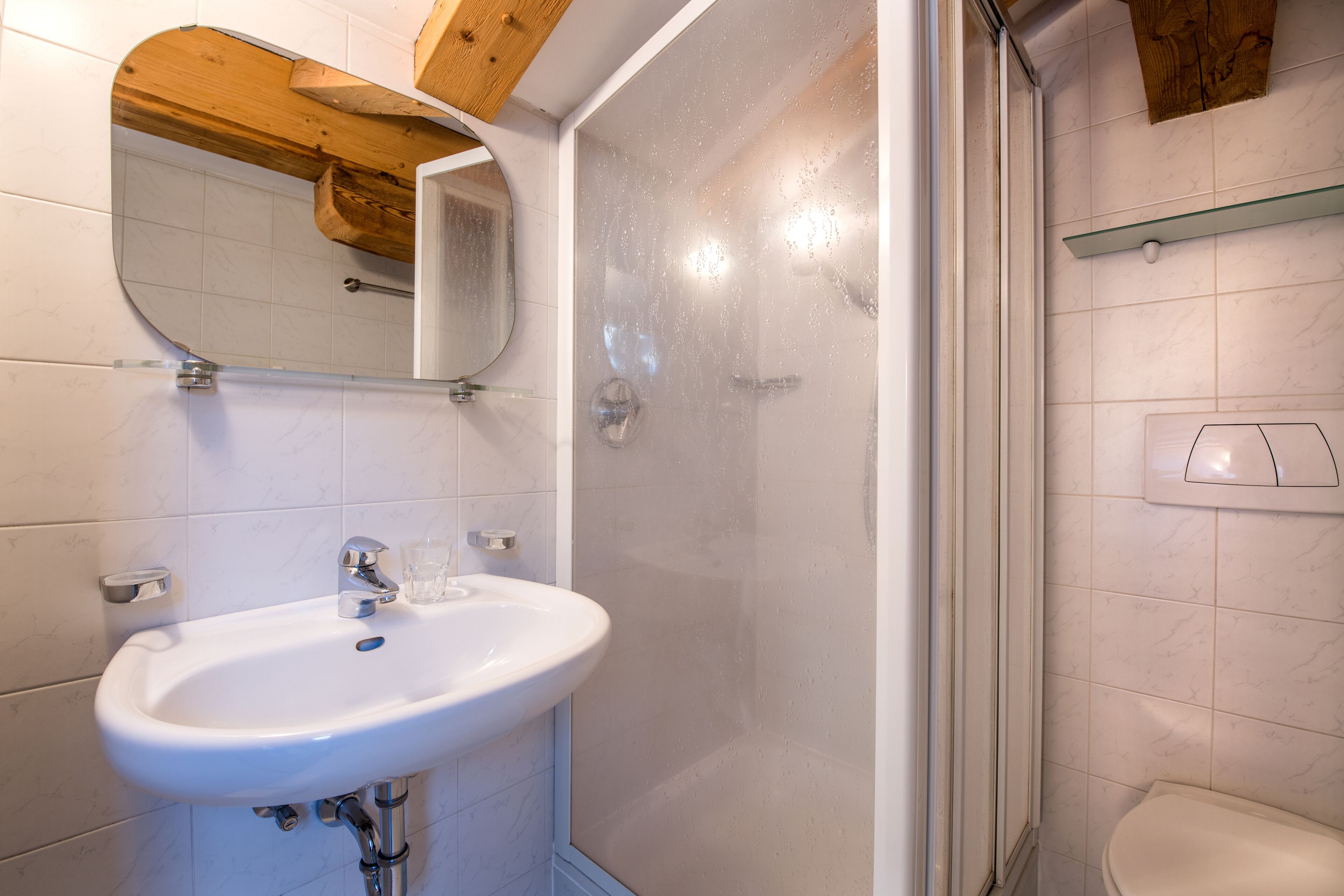 A bathroom with a white sink, a mirror, and a shower area.