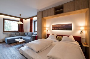 Habitación de hotel moderna con una cama grande, un sofá, una mesita y un cuadro en la pared.