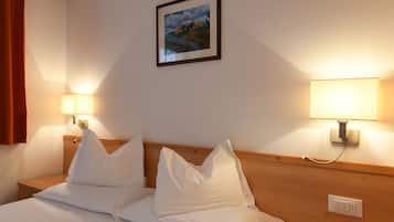 Camera d'albergo con un letto rifatto, due lampade ai comodini, un quadro appeso alla parete e una testiera in legno.