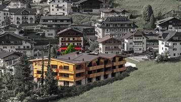 Un edificio moderno de varios pisos con balcones, rodeado de casas tradicionales en una ladera.