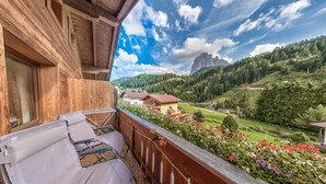 Un balcón de madera con vistas a un paisaje montañoso y un pueblo en la falda de la montaña.