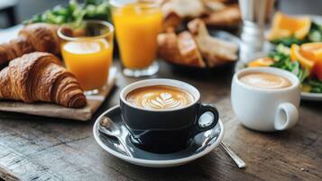 A breakfast setting with croissants, orange juice, and coffee cups on a wooden table.