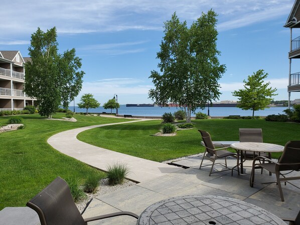 A patio area with outdoor seating, a curved pathway, and a view of the water and distant cityscape. - Bridgeport Waterfront Resort (Sturgeon Bay)