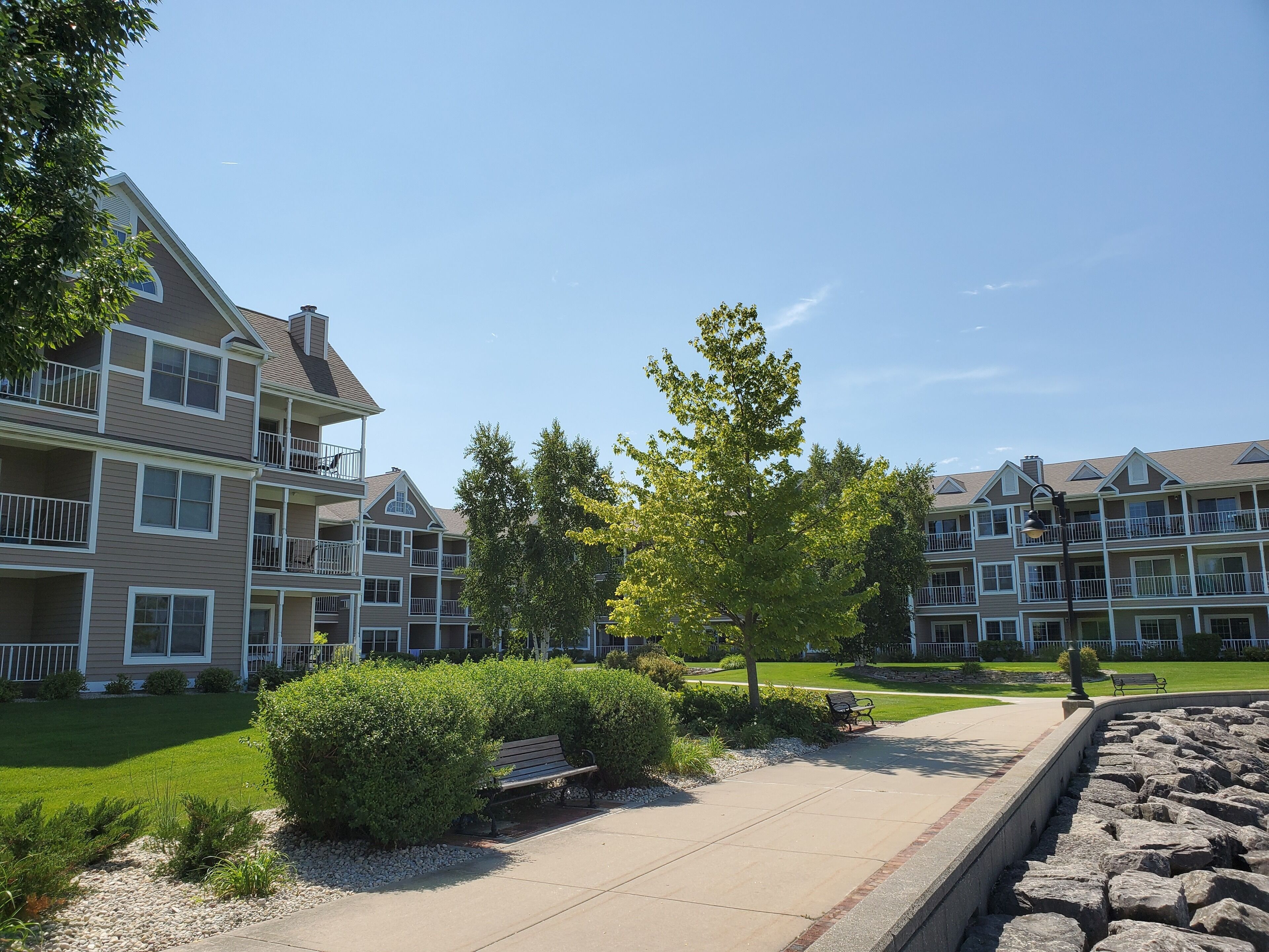 A residential building with multiple balconies, a well-maintained lawn, and a paved walkway.