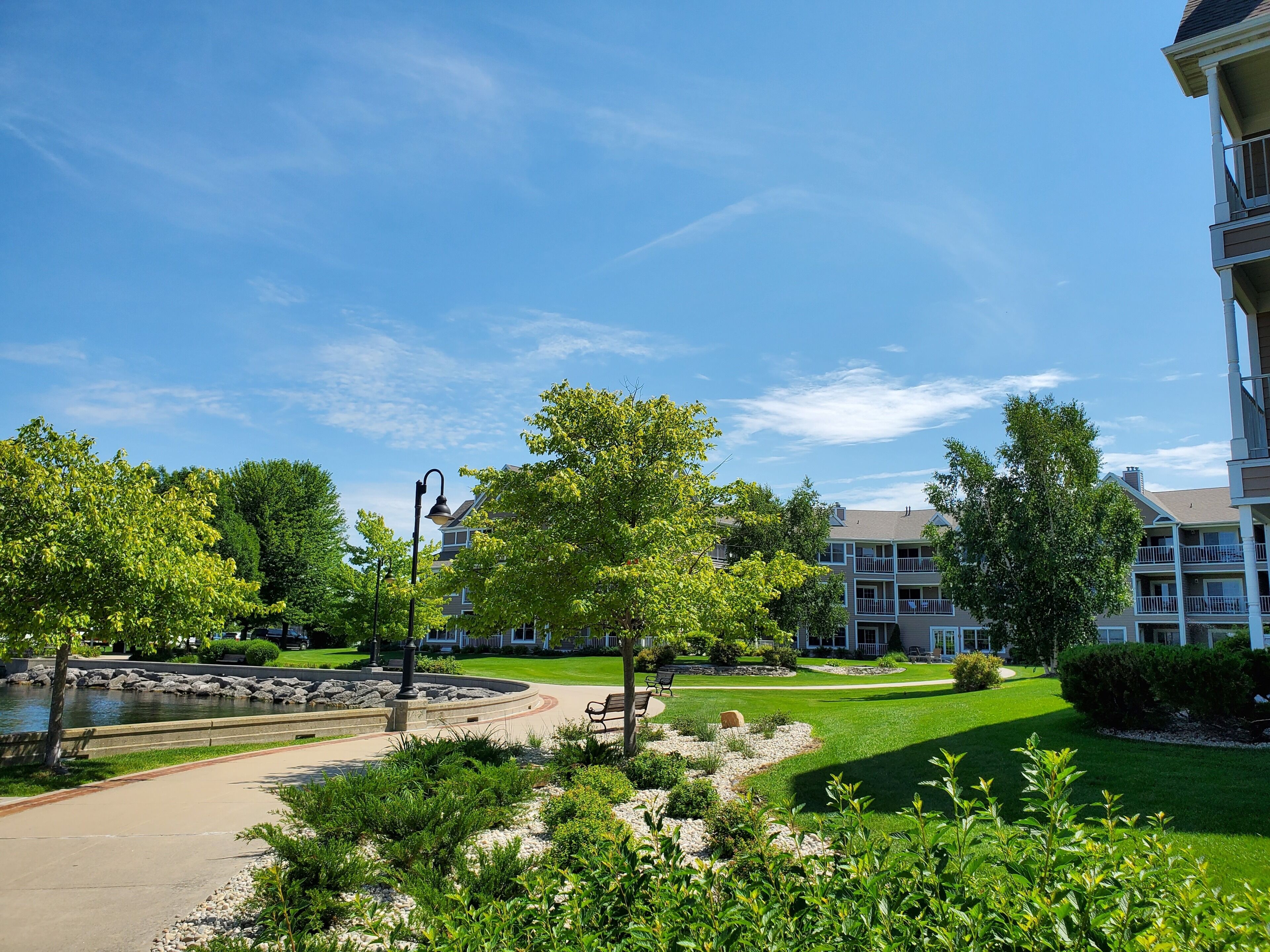A residential area with a well-maintained lawn, a walking path, and a small pond.