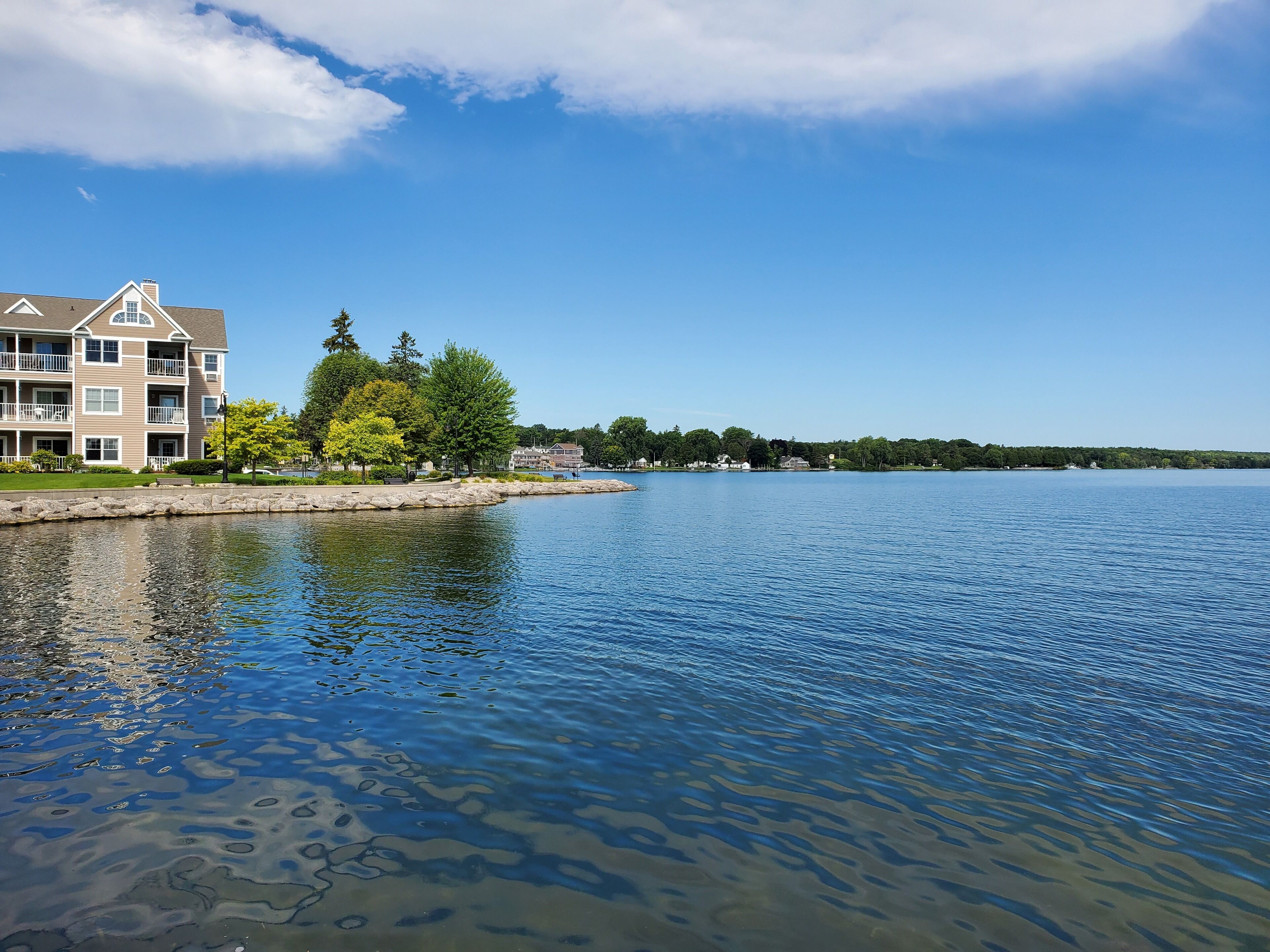 Un hôtel situé au bord de l’eau, avec un grand bâtiment, un quai et un lac paisible.