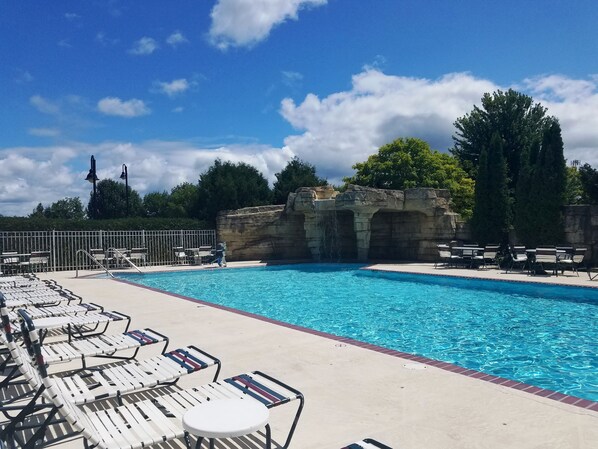 A swimming pool with lounge chairs and a rocky waterfall feature. - Bridgeport Waterfront Resort (Sturgeon Bay)