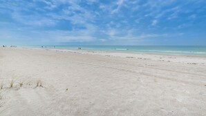 Una extensa playa de arena con cielo despejado y mar tranquilo.