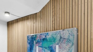 Una habitación moderna con un panel de madera y un cuadro abstracto grande con una letra 'H' destacada.