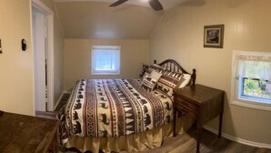 A bedroom with a large bed, two windows, a ceiling fan, and a small table. - Sportsman Cottage - Raystown Lake Vacation Rentals, Aunt Susie's (Hesston)