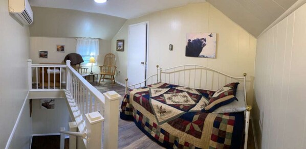Une chambre à coucher avec un lit, une chaise, un bureau et un escalier.