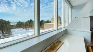 Una habitación con un ventanal grande que da a un paisaje nevado y un edificio distante.