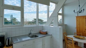 Una cocina con fregadero, armarios y un comedor con mesa y sillas.
