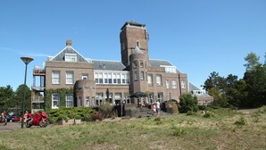 Ein großes Backsteingebäude mit einem markanten Turm und zahlreichen Fenstern.