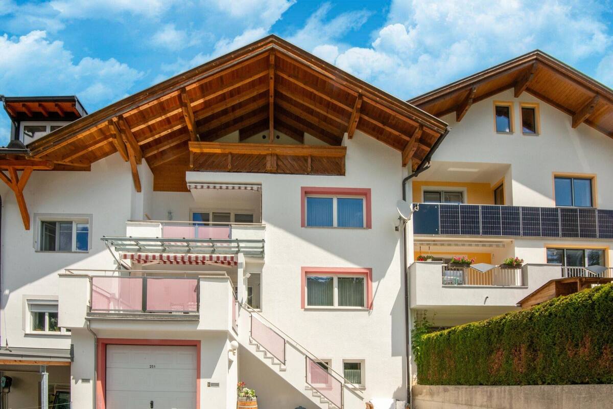 Ein mehrgeschossiges Gebäude mit Holzdach, Balkonen und einer Garage.
