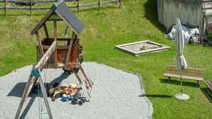 A playground with a wooden swing set, a sandbox, and a bench.