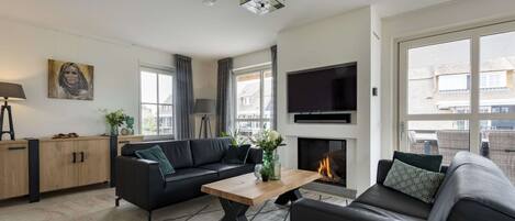 Ein modernes Wohnzimmer mit einer schwarzen Ledersofa, einem Holztisch und einem Kamin.