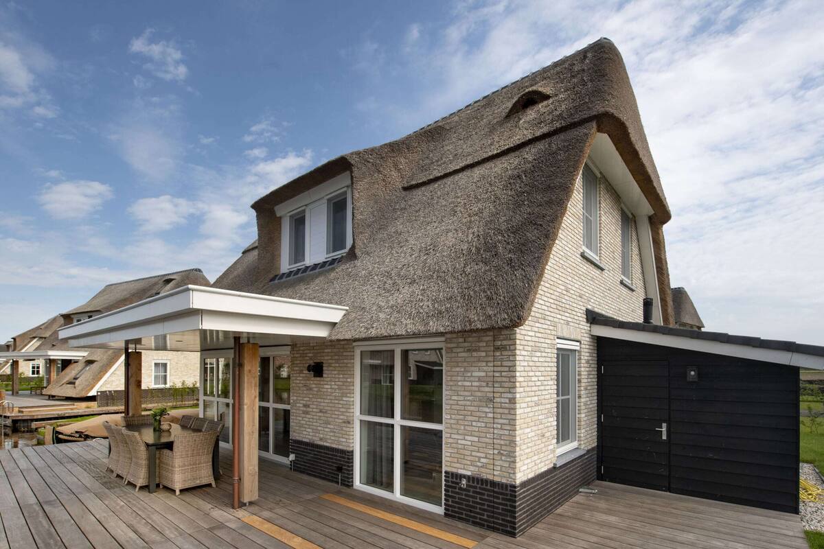 A modern house with a sloped roof, large windows, and a wooden deck.