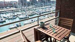 A balcony with a view of a marina filled with boats, a wooden table, and a chair. - Modern Apartment in The Hague (The Hague)