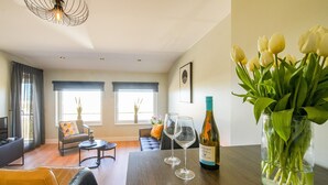 Ein modernes Wohnzimmer mit einem Holztisch, zwei Stühlen, einer Couch und einem Strauß Tulpen.