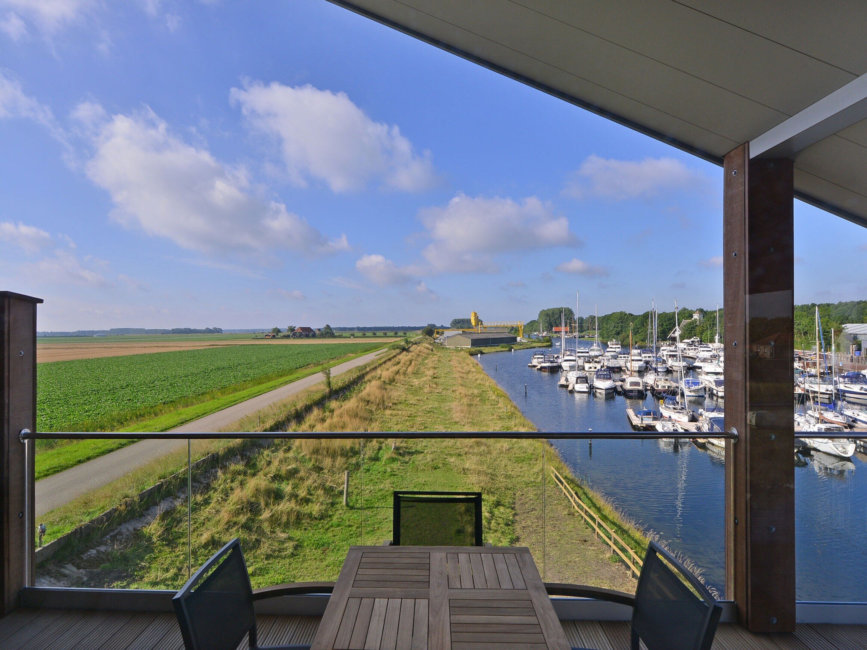 A balcony with a view of a marina and fields.