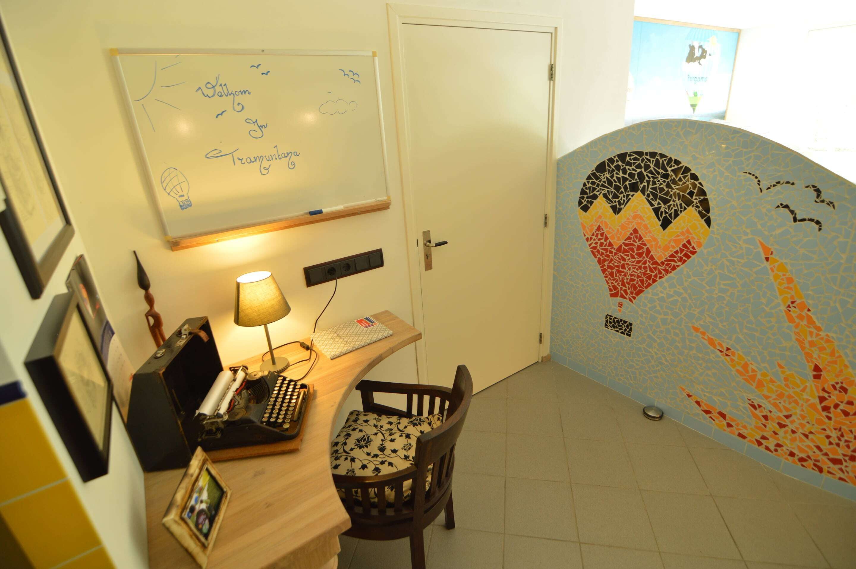 A room with a desk, chair, whiteboard, and a wall with a mosaic design.