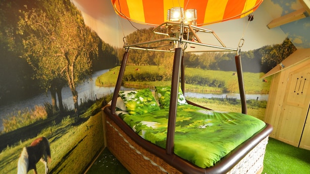 A wicker four-poster bed with a green bedspread and a canopy overhead. - Holiday Home in Haaren Near De Efteling (Haaren)