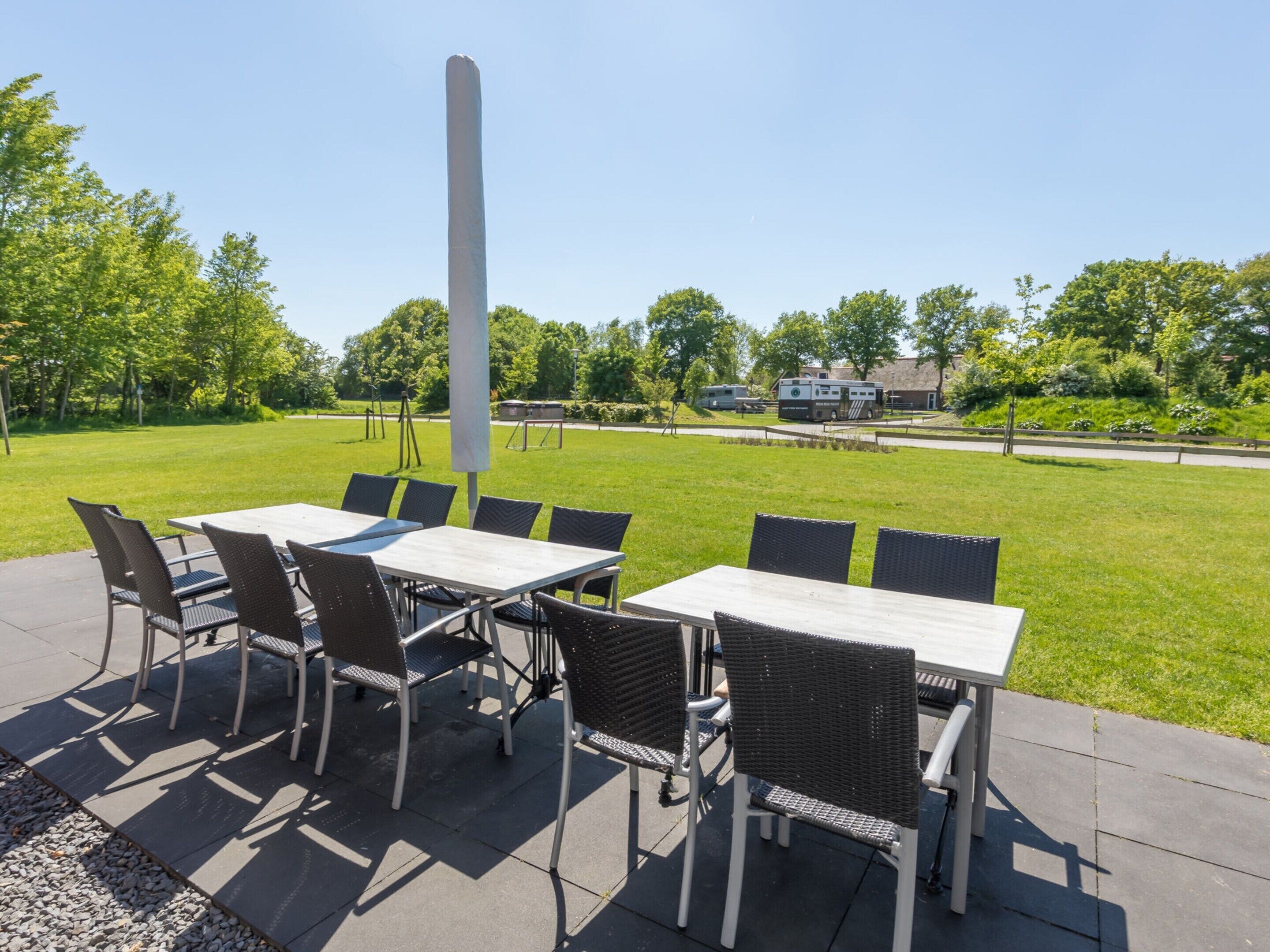 An outdoor patio with a table and chairs, surrounded by a grassy area and trees.