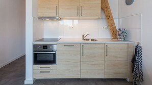 A modern kitchen with light wood cabinets, a stainless steel sink, and a built-in oven. - Apartment in Koudekerke Near Seabeach (Koudekerke)