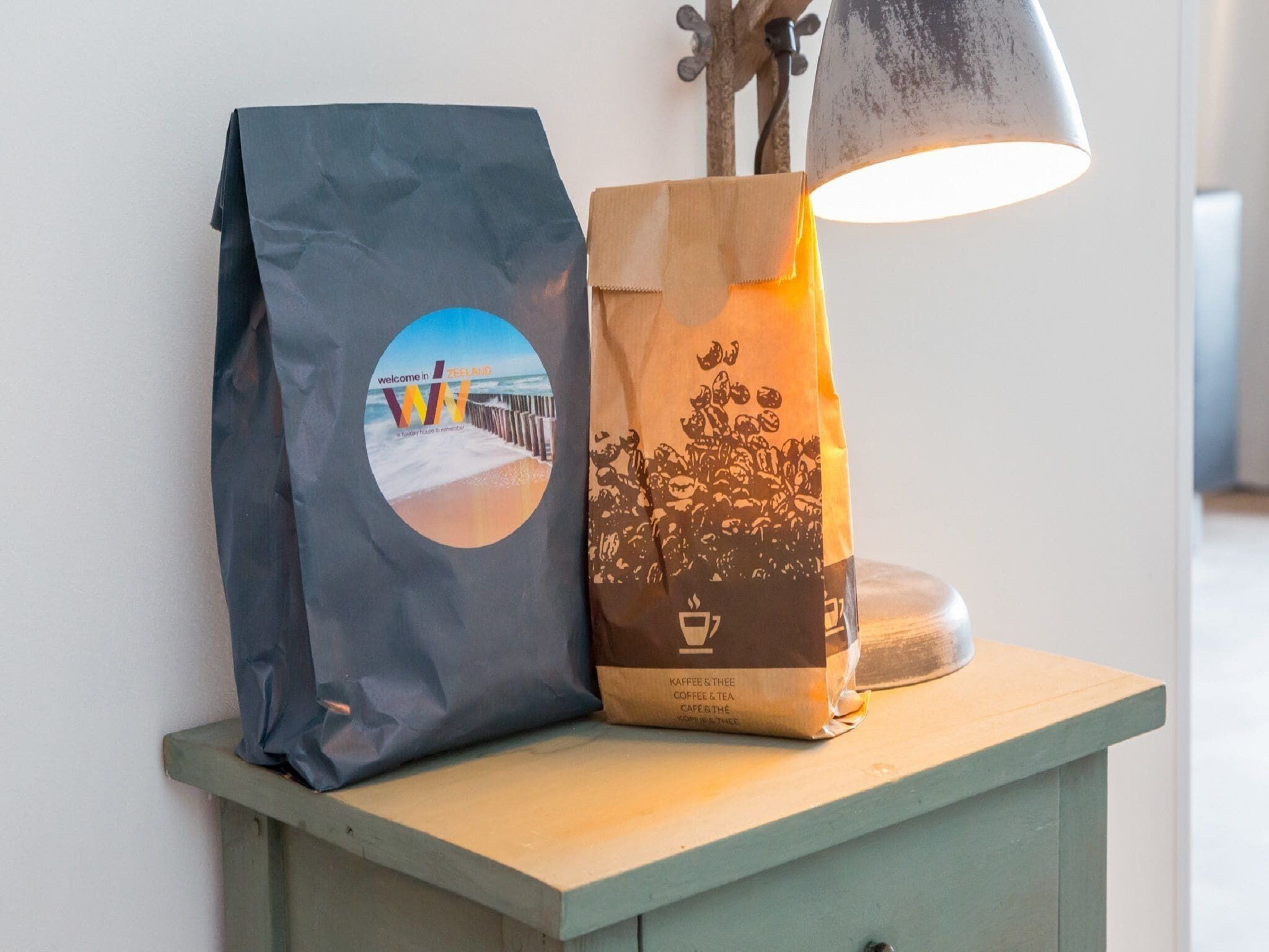 A bag with a beach scene and text, and a lamp on a wooden table.