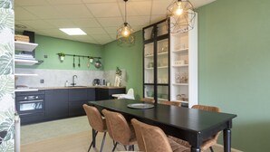 A modern kitchen with a dining area, featuring a black dining table, brown chairs, and pendant lighting. - Nice Apartment With Garden Near the North Sea (Julianadorp)