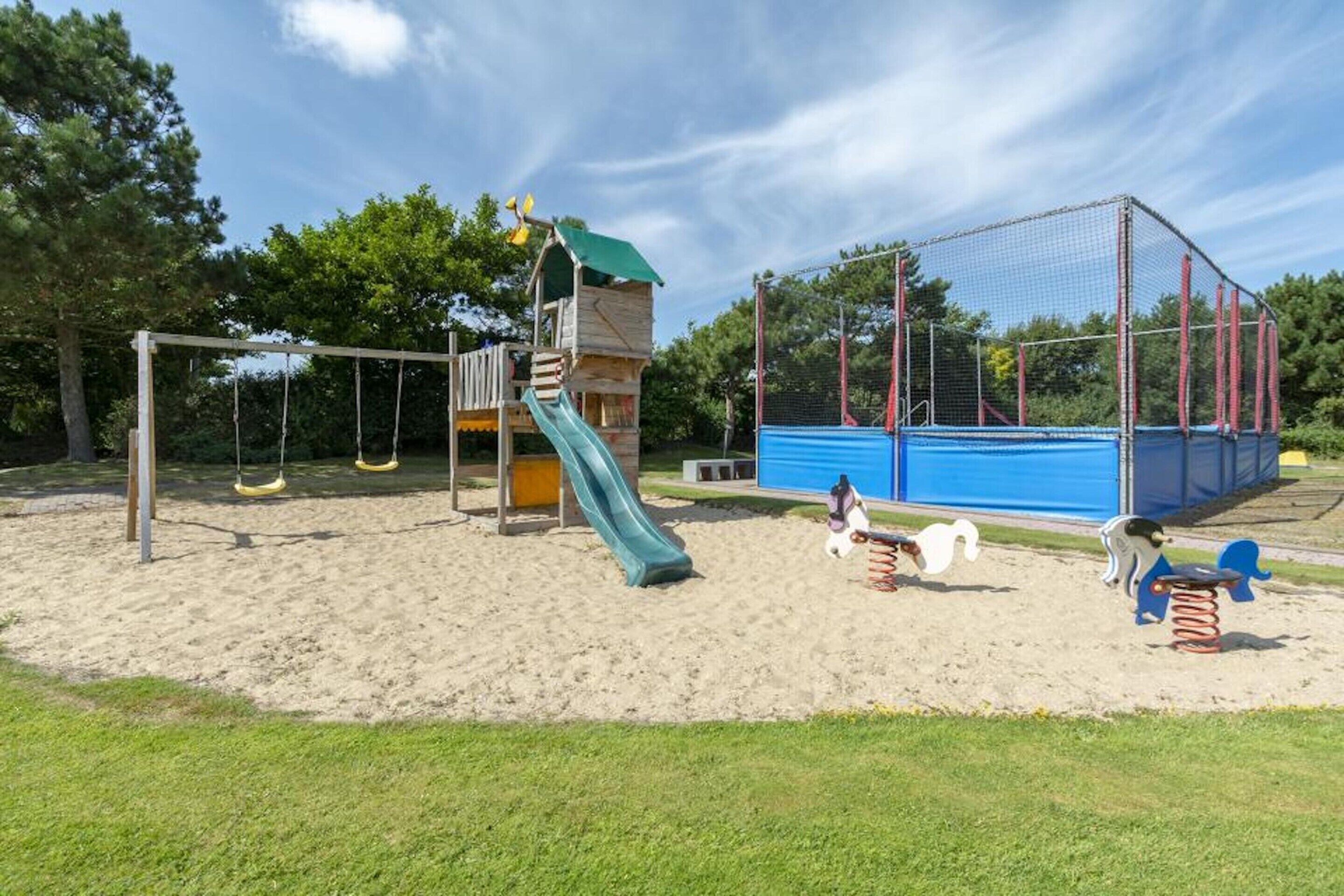 Un parque infantil con tobogán, columpios y una estructura para escalar.