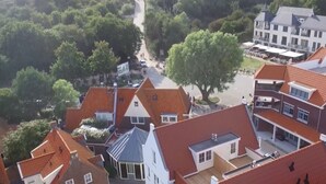 A residential area with red-tiled roofs, white houses, and a large tree.